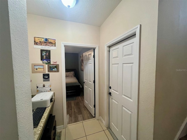 corridor with light tile patterned floors and a textured ceiling