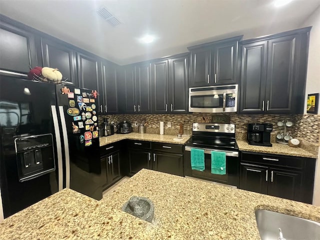 kitchen featuring light stone countertops, decorative backsplash, and stainless steel appliances