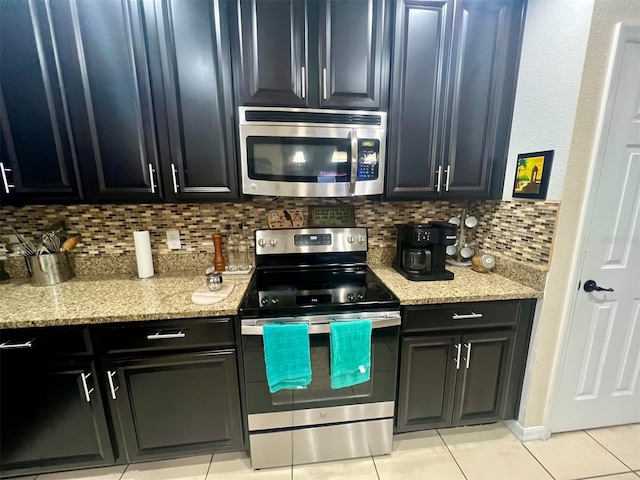 kitchen featuring light stone counters, backsplash, light tile patterned floors, and appliances with stainless steel finishes