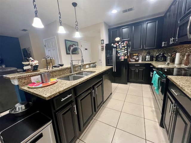 kitchen with sink, backsplash, hanging light fixtures, black appliances, and a center island with sink