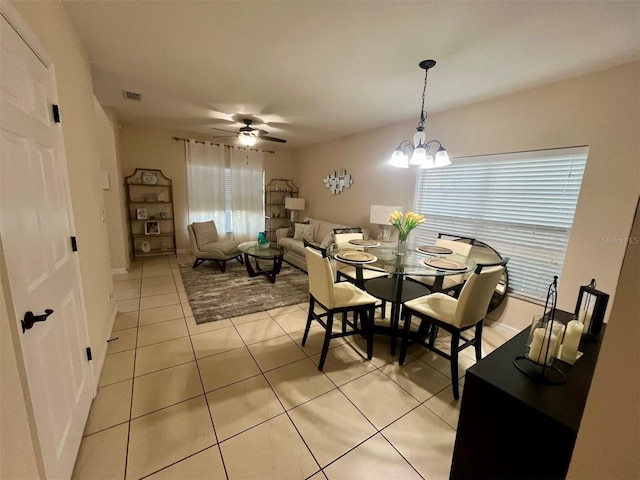 dining area with light tile patterned flooring and ceiling fan with notable chandelier