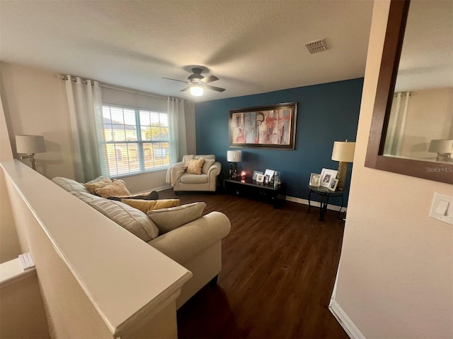 living room featuring ceiling fan, dark hardwood / wood-style floors, and a textured ceiling