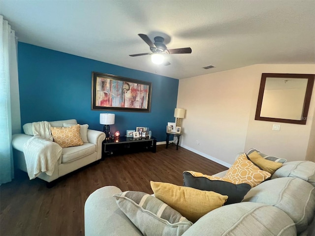 living room featuring dark wood-type flooring, ceiling fan, and a textured ceiling