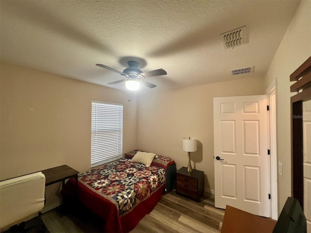 bedroom featuring ceiling fan, a textured ceiling, and light wood-type flooring