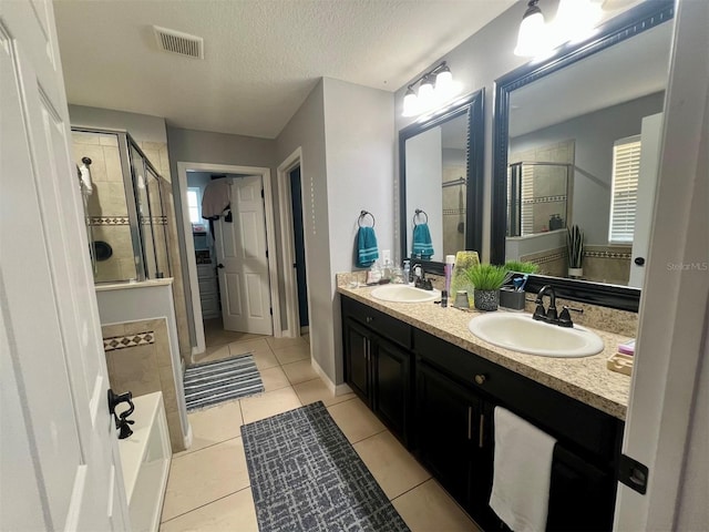 bathroom with vanity, plus walk in shower, a healthy amount of sunlight, a textured ceiling, and tile patterned floors