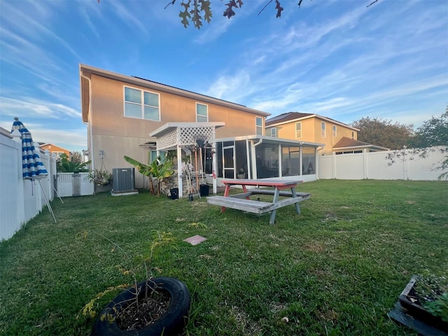 back of house featuring a lawn, a sunroom, and central air condition unit