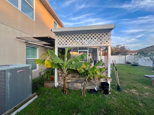 exterior space with central AC unit and a lawn