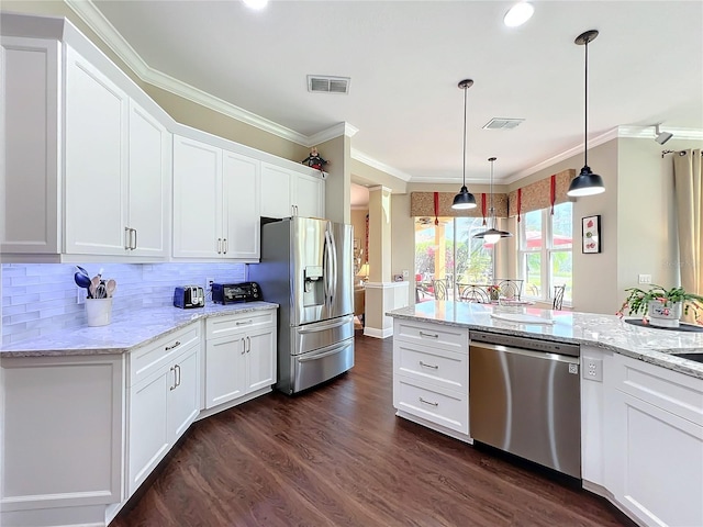 kitchen featuring white cabinetry, crown molding, light stone counters, appliances with stainless steel finishes, and pendant lighting