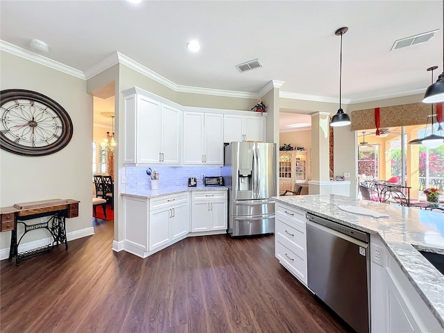 kitchen with pendant lighting, appliances with stainless steel finishes, light stone countertops, white cabinets, and dark hardwood / wood-style flooring