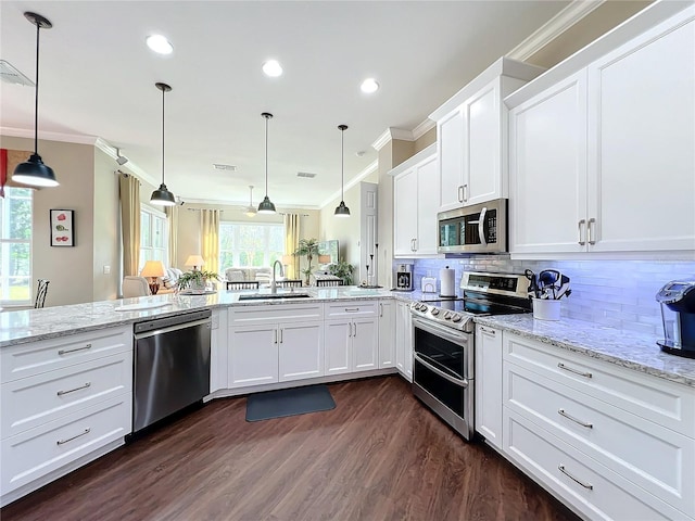 kitchen featuring stainless steel appliances, white cabinetry, sink, and decorative light fixtures