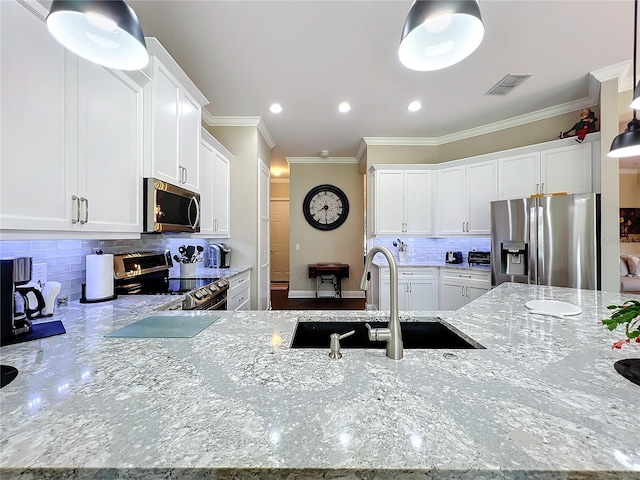 kitchen featuring pendant lighting, sink, appliances with stainless steel finishes, white cabinetry, and light stone countertops