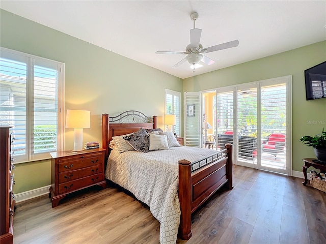 bedroom featuring multiple windows, wood-type flooring, access to exterior, and ceiling fan