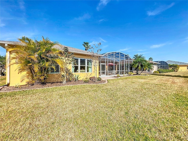 rear view of house with a yard and glass enclosure