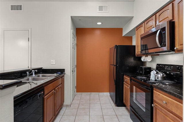 kitchen featuring sink, dark stone countertops, light tile patterned floors, and black appliances