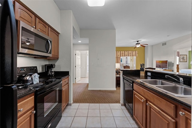 kitchen with sink, black appliances, dark stone counters, and ceiling fan