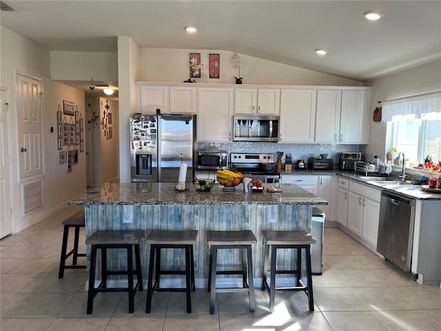 kitchen with white cabinetry, stainless steel appliances, sink, and a kitchen island