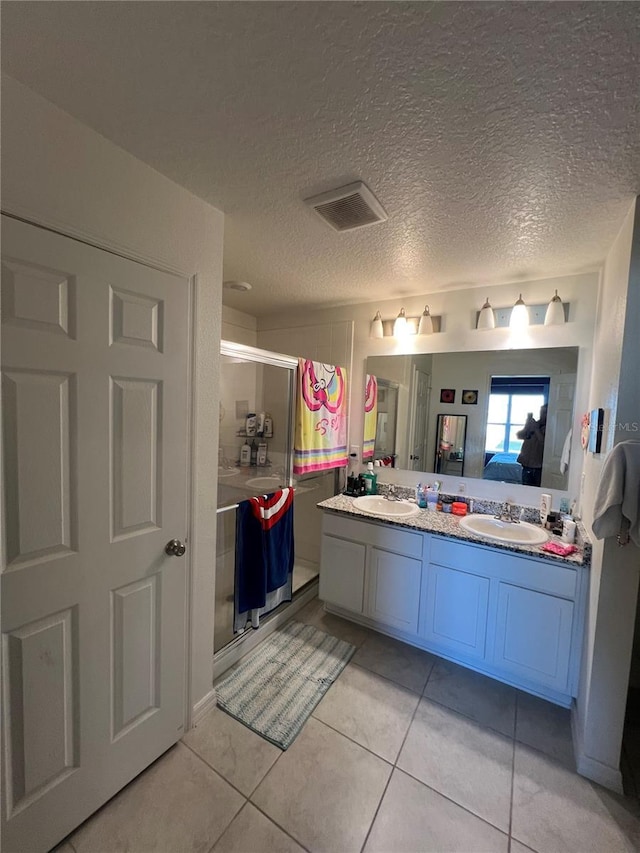 bathroom with tile patterned flooring, vanity, a textured ceiling, and walk in shower