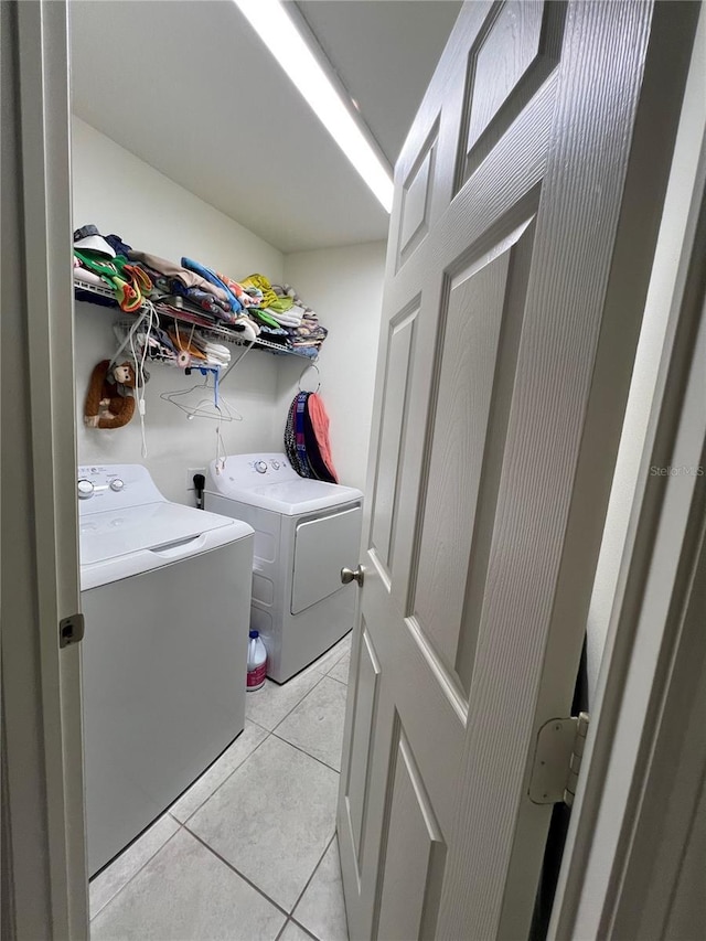 clothes washing area featuring light tile patterned floors and washer and dryer