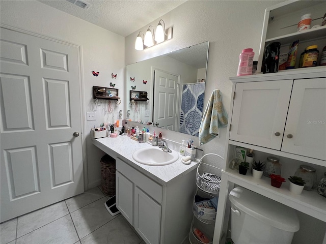 bathroom with tile patterned flooring, vanity, toilet, and a textured ceiling