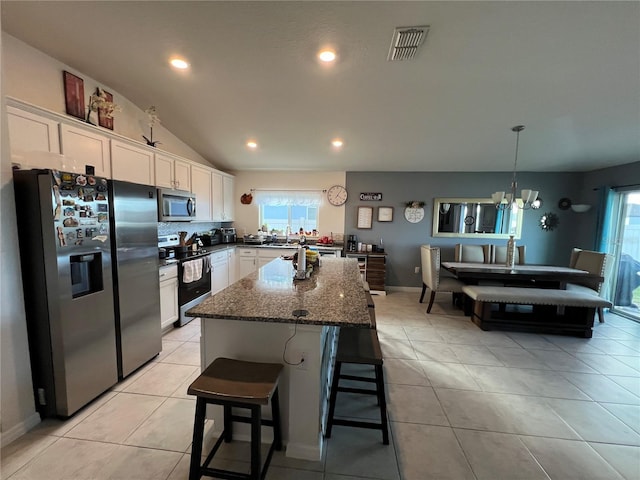 kitchen with a kitchen island, decorative light fixtures, white cabinets, dark stone counters, and stainless steel appliances