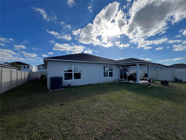 rear view of property featuring a lawn, a patio, and central air condition unit