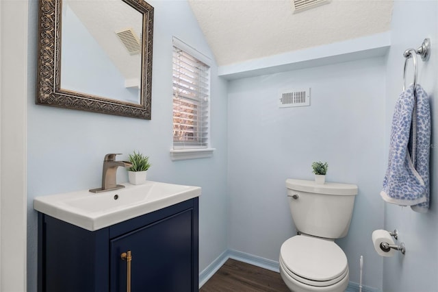 bathroom featuring hardwood / wood-style floors, vanity, a textured ceiling, vaulted ceiling, and toilet