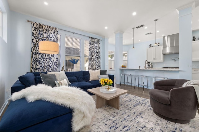 living room featuring sink, light hardwood / wood-style flooring, and ornate columns