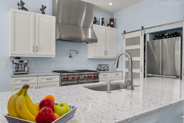 kitchen featuring sink, extractor fan, appliances with stainless steel finishes, light stone countertops, and white cabinets