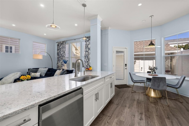 kitchen with pendant lighting, sink, white cabinetry, light stone countertops, and stainless steel dishwasher