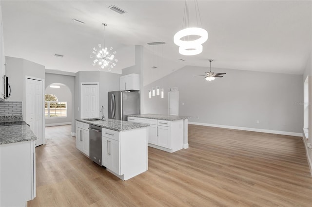 kitchen featuring sink, white cabinetry, stainless steel appliances, a center island with sink, and decorative light fixtures