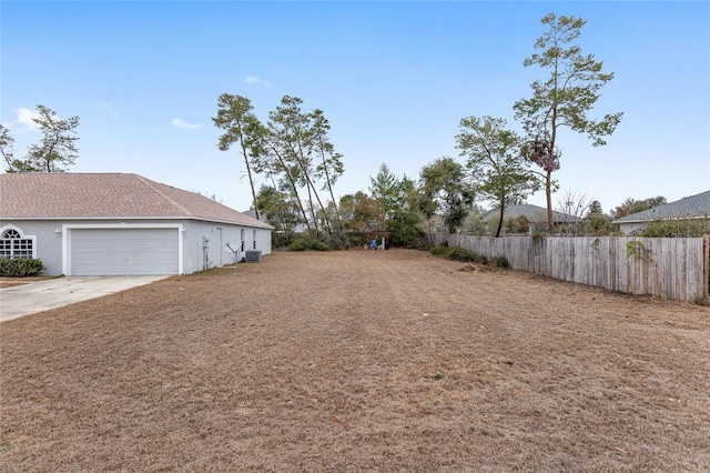 view of yard featuring a garage and central AC