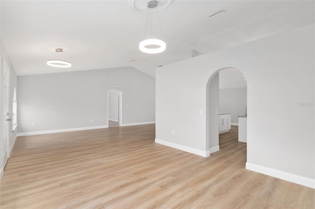 unfurnished room featuring lofted ceiling and light wood-type flooring