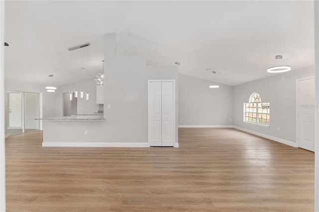 unfurnished living room featuring lofted ceiling and light hardwood / wood-style flooring