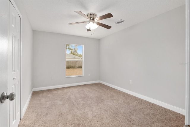 unfurnished room with light carpet, ceiling fan, and a textured ceiling