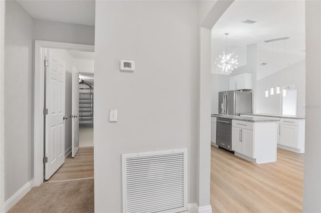 hallway featuring vaulted ceiling, a notable chandelier, and light hardwood / wood-style flooring