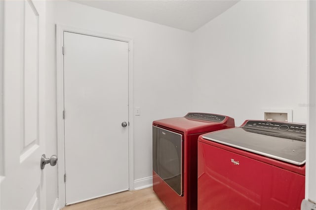 laundry area with washing machine and dryer and light hardwood / wood-style flooring