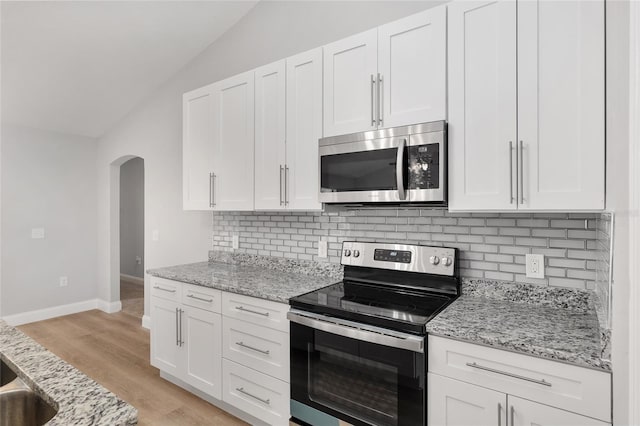 kitchen with stainless steel appliances, white cabinetry, and light stone counters