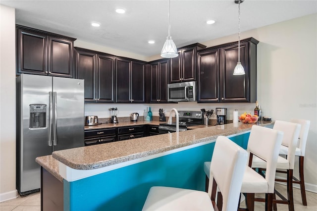 kitchen with hanging light fixtures, appliances with stainless steel finishes, a breakfast bar, and kitchen peninsula