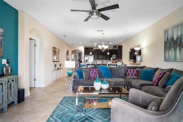 tiled living room with ceiling fan with notable chandelier