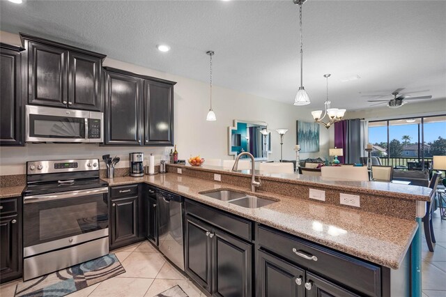 kitchen featuring ceiling fan with notable chandelier, light stone countertops, a sink, and stainless steel appliances