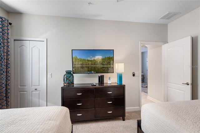 bedroom featuring light colored carpet, visible vents, a closet, and baseboards