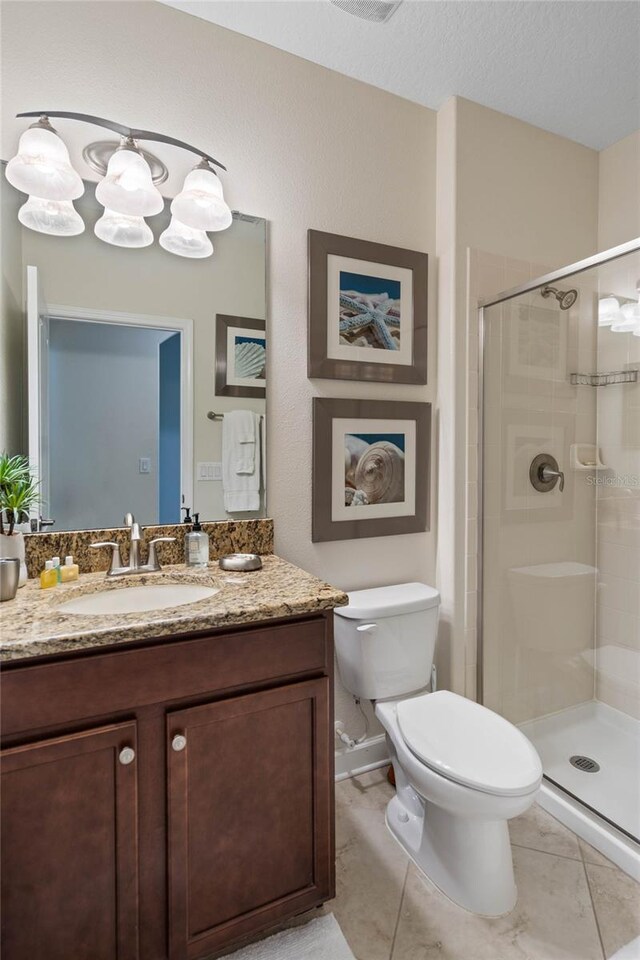 bathroom featuring a textured ceiling, toilet, tile patterned floors, vanity, and a stall shower