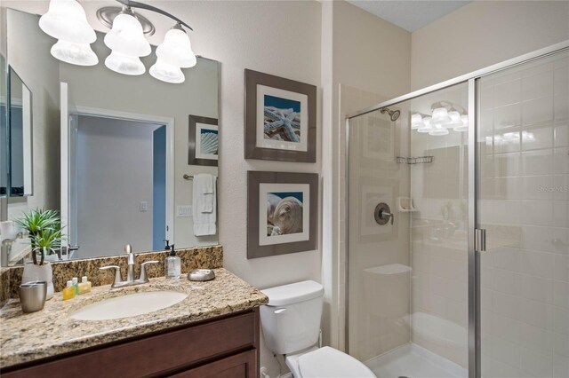 bathroom with a shower stall, toilet, vanity, and an inviting chandelier