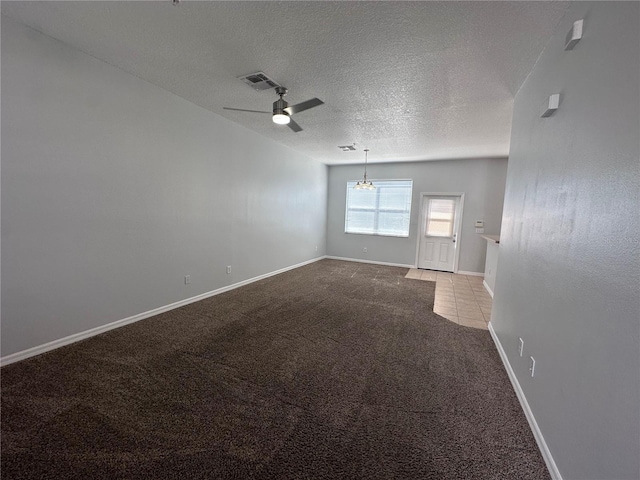 empty room with ceiling fan with notable chandelier, carpet, and a textured ceiling