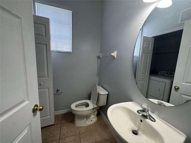 bathroom with tile patterned floors, toilet, washer / dryer, and sink