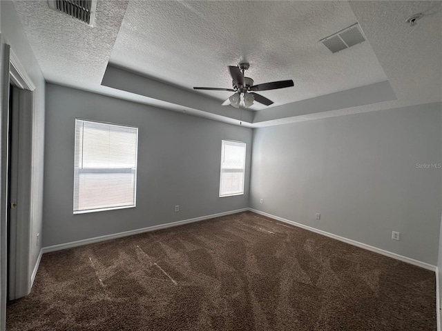 carpeted spare room with a textured ceiling, a raised ceiling, and ceiling fan