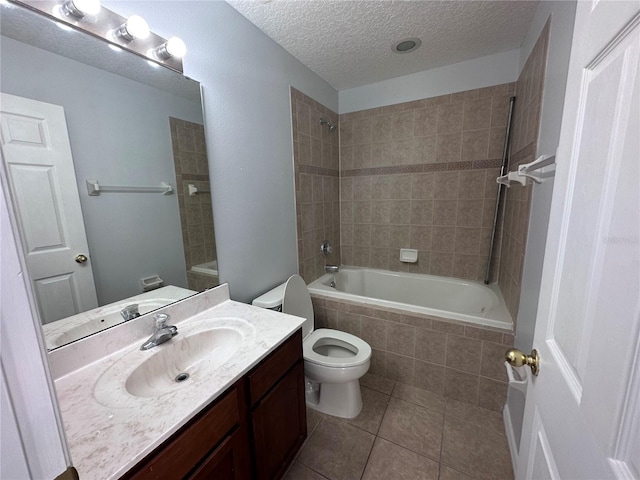 full bathroom with tiled shower / bath, vanity, toilet, tile patterned floors, and a textured ceiling