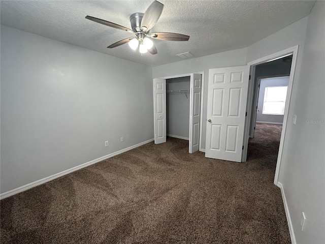 unfurnished bedroom featuring ceiling fan, dark carpet, a closet, and a textured ceiling