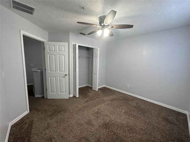 unfurnished bedroom with ceiling fan, dark carpet, a closet, and a textured ceiling