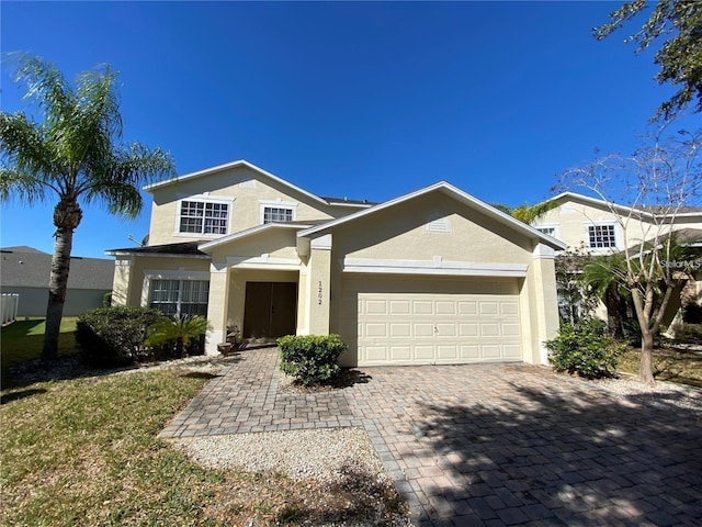 traditional-style house with stucco siding, decorative driveway, and a garage